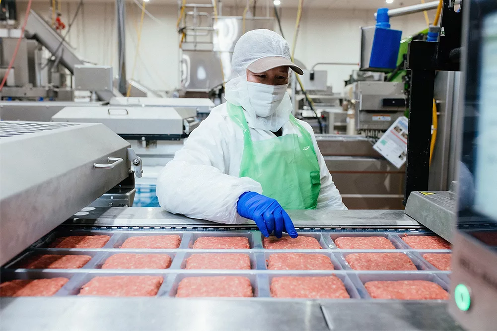 A worker in a meat processing plant checking meat